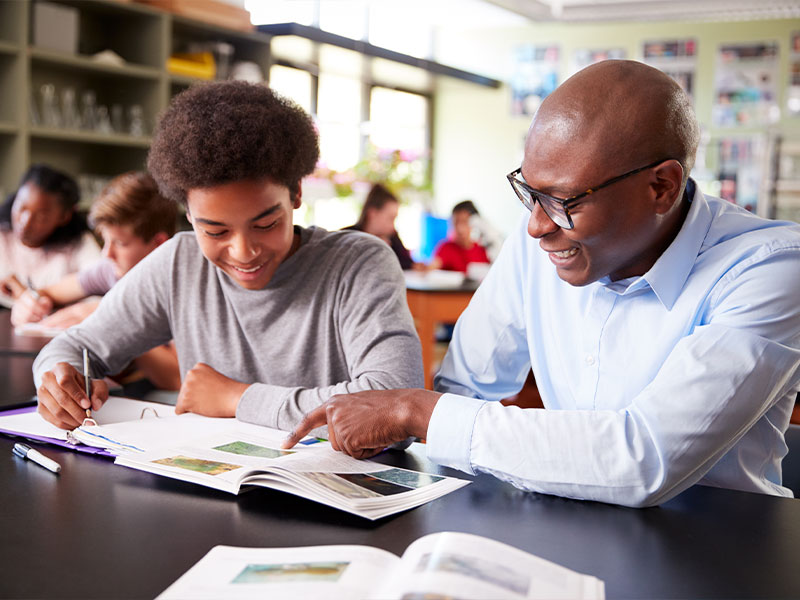 Teacher assisting student with textbook