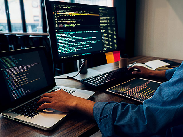 Student coding on two screens